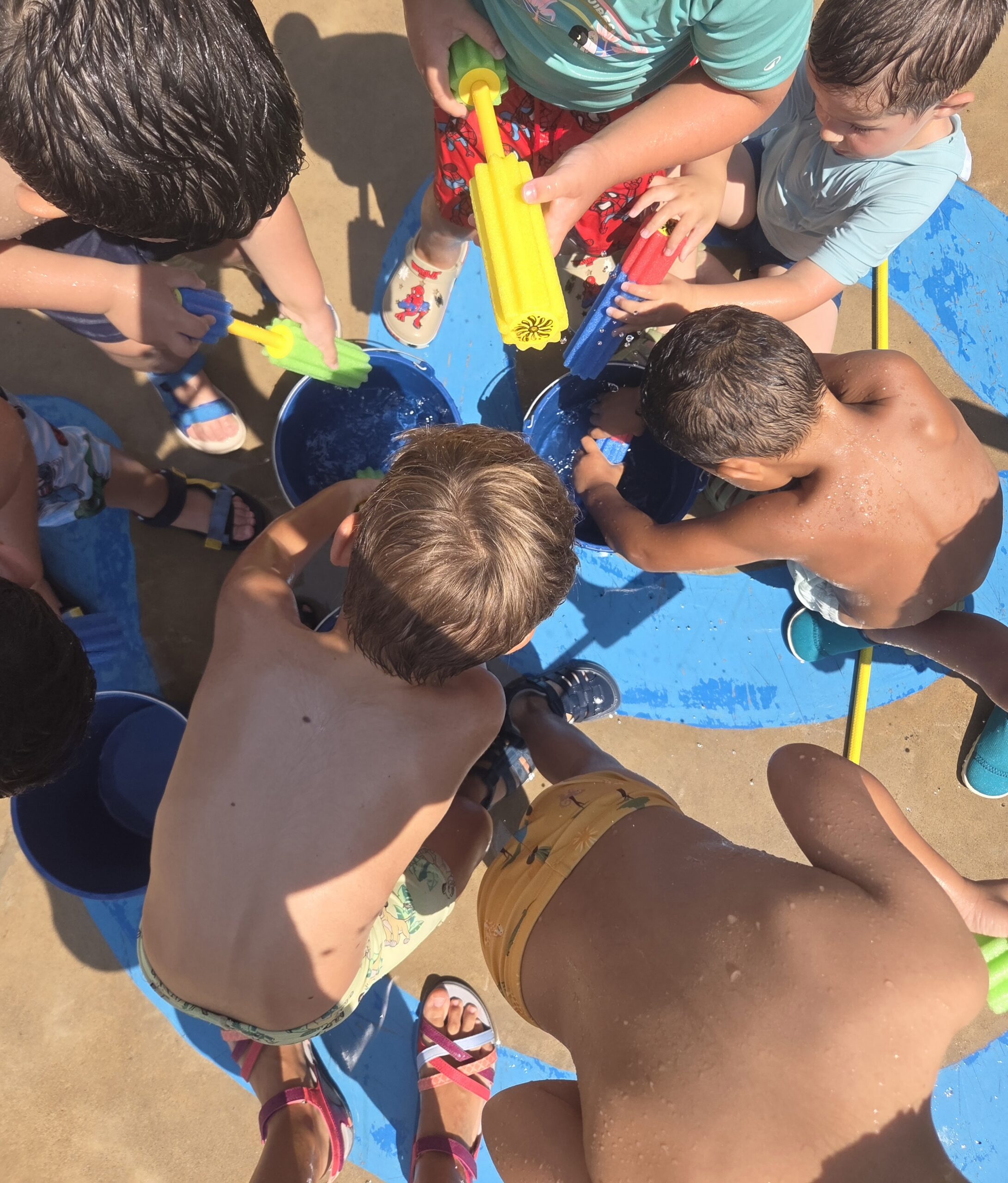 Niños en bañador llenando pistolas de agua durante una actividad de ocio educativo